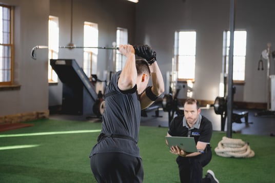 Golfer being assessed in his swing during sports physical therapy.