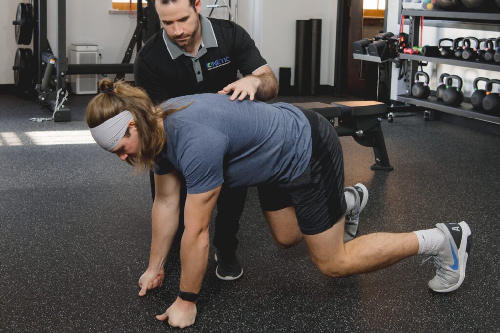 Athlete working with a physical therapist doing a bear crawl exercise.