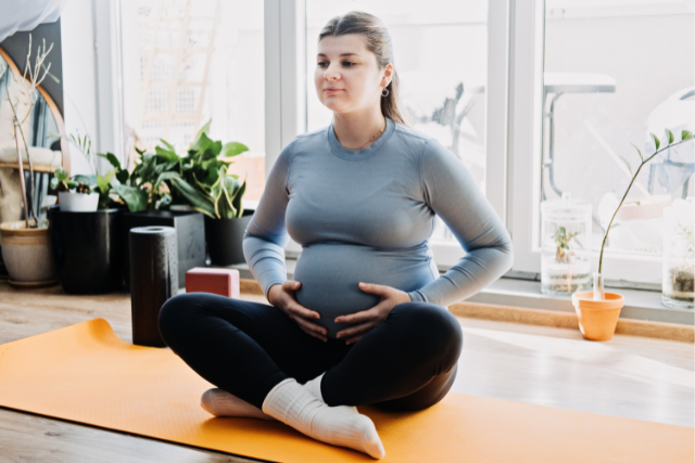 Pregnant woman bracing her core during breath work in training her pelvic floor.